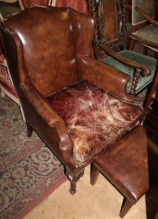 A Georgian style mahogany and brown leather wing armchair & stool